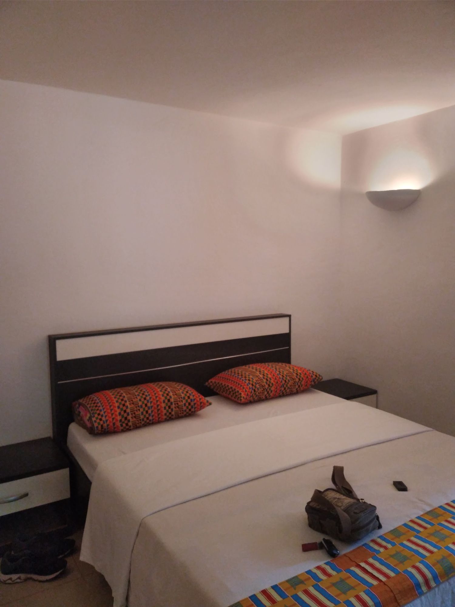 Chambre double avec tête de lit en bois et coussins colorés